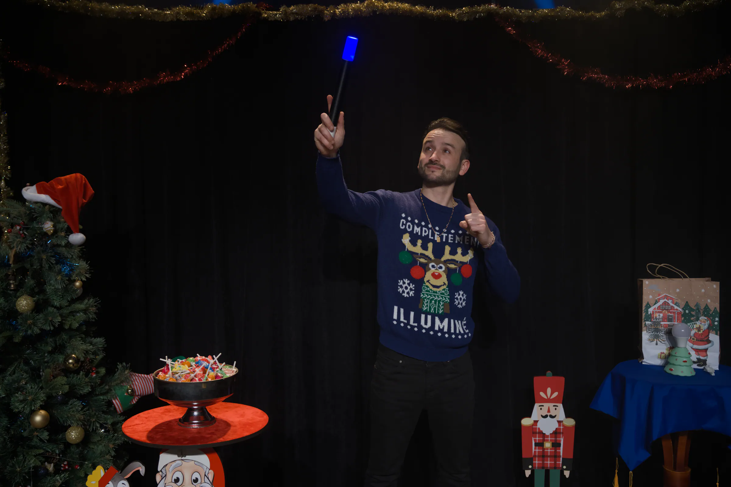 Tyson Dumas, magicien, brandit une baguette lumineuse bleue pendant son spectacle de Noël pour enfants